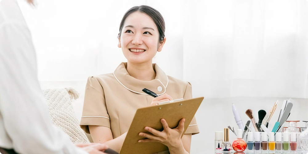 ネイルサロンで清潔感のある身だしなみを整えたネイリストが笑顔で接客するイメージ
